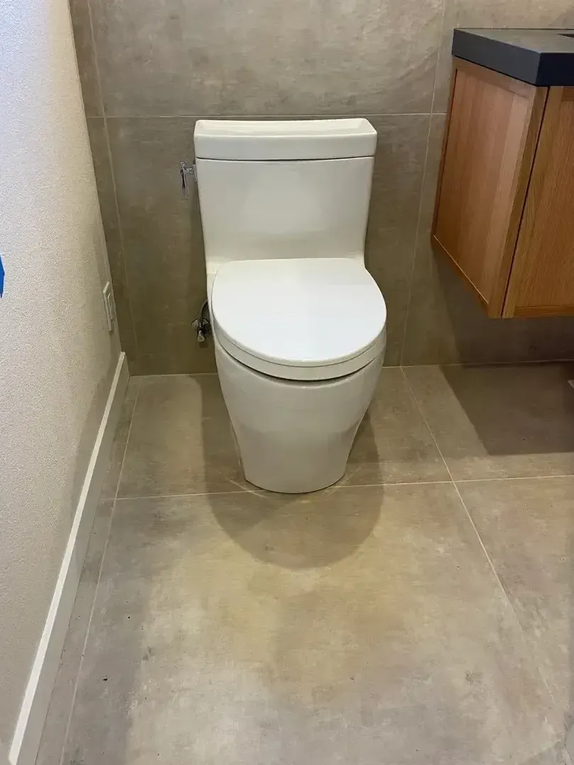 New white toilet in bathroom with tile floor and wood cabinet