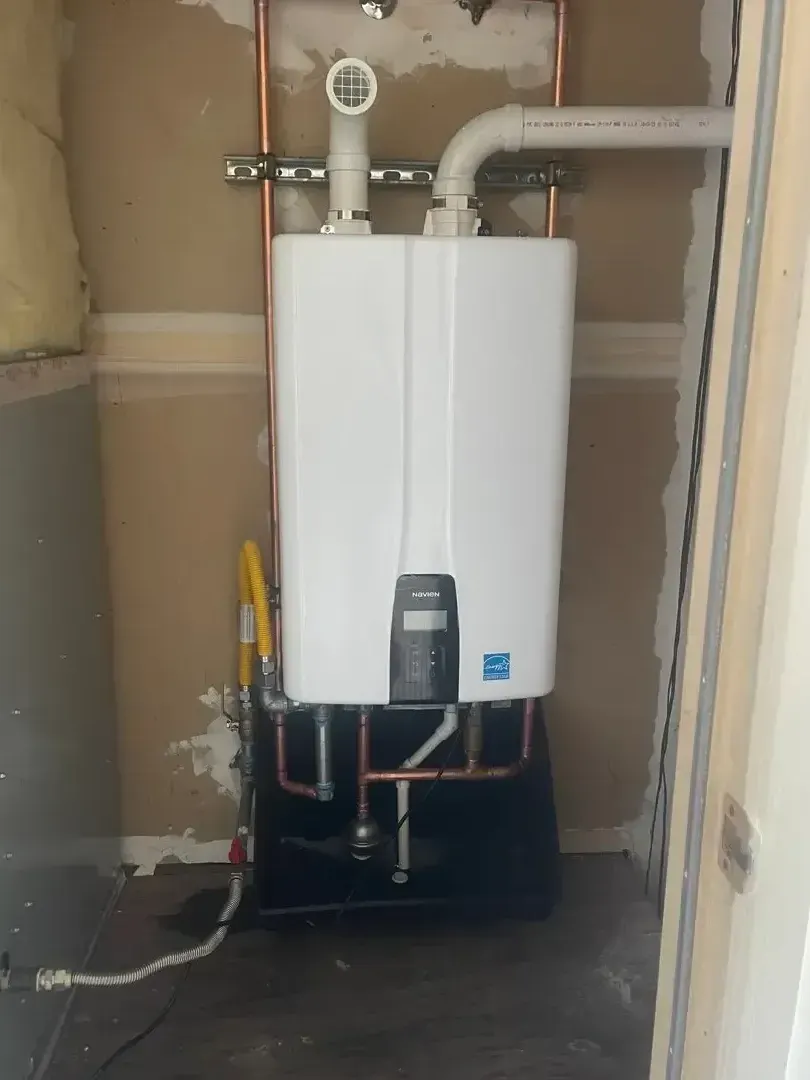 White tankless water heater installed on wall with copper pipes
